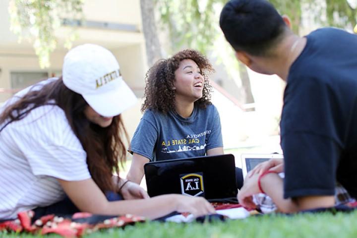 Three students sitting on lawn